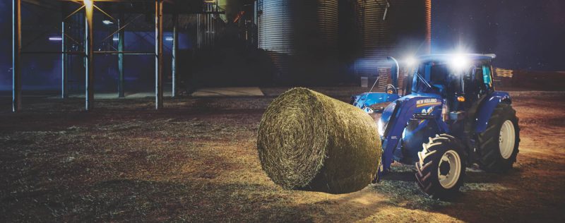 tractor moving round bale at night
